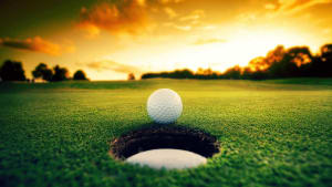 A golf ball is sitting in a hole at sunset.